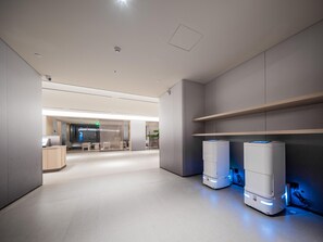 A modern interior with a clean, minimalist design, featuring a reception area, seating, and two large, illuminated devices on the right. - JI Hotel (xian Jiaotong University Qinglong Templ (Xi'an)