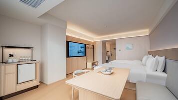 Une chambre d’hôtel moderne équipée d’un lit, d’un bureau, d’une télévision et d’une kitchenette.