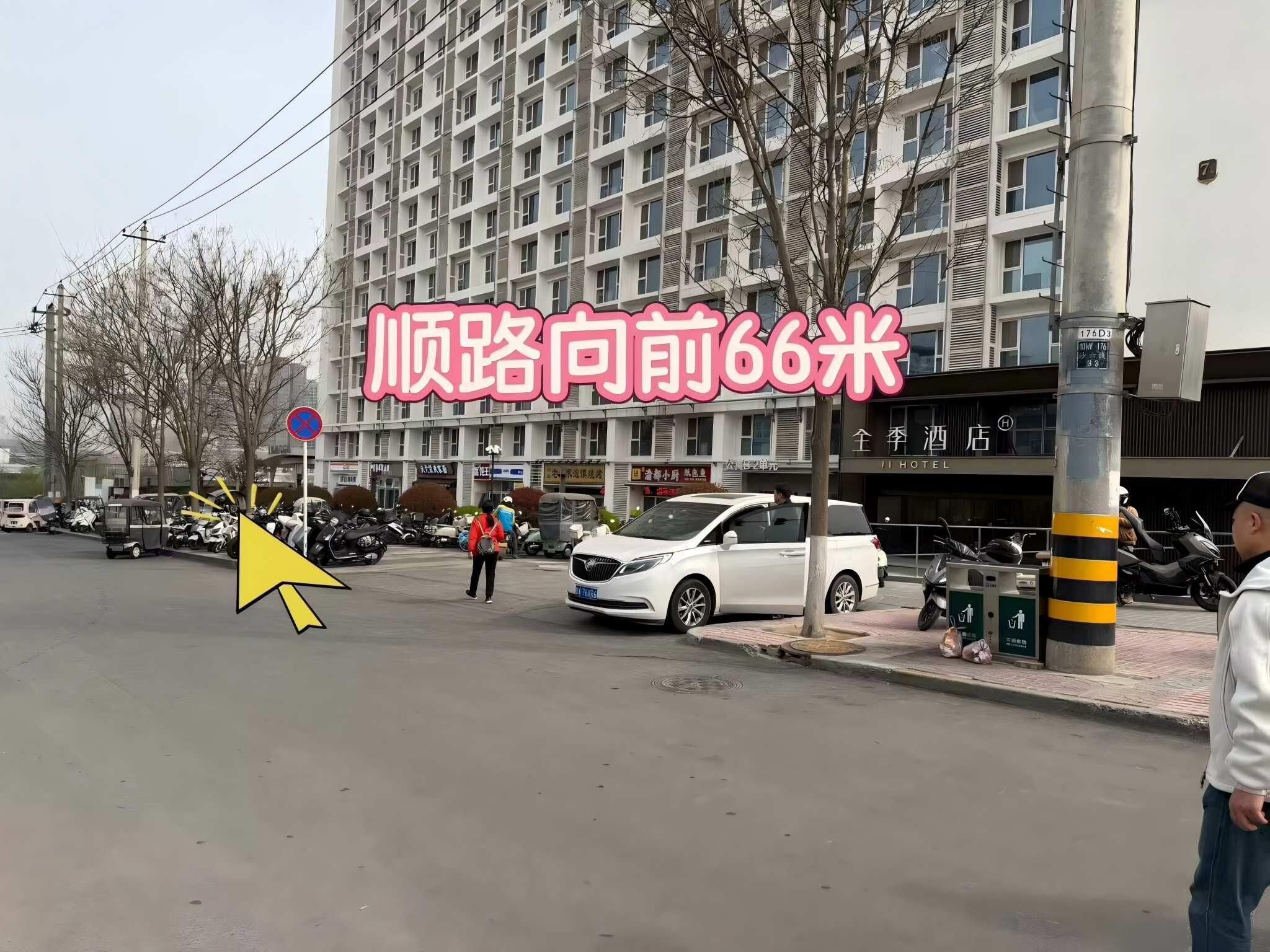 A multi-story building with a sign indicating a hotel. There are parked vehicles and a pedestrian on the sidewalk.