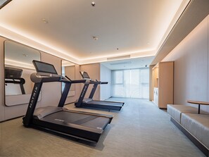 Un gimnasio moderno con cintas de correr, un espejo y un sofá.