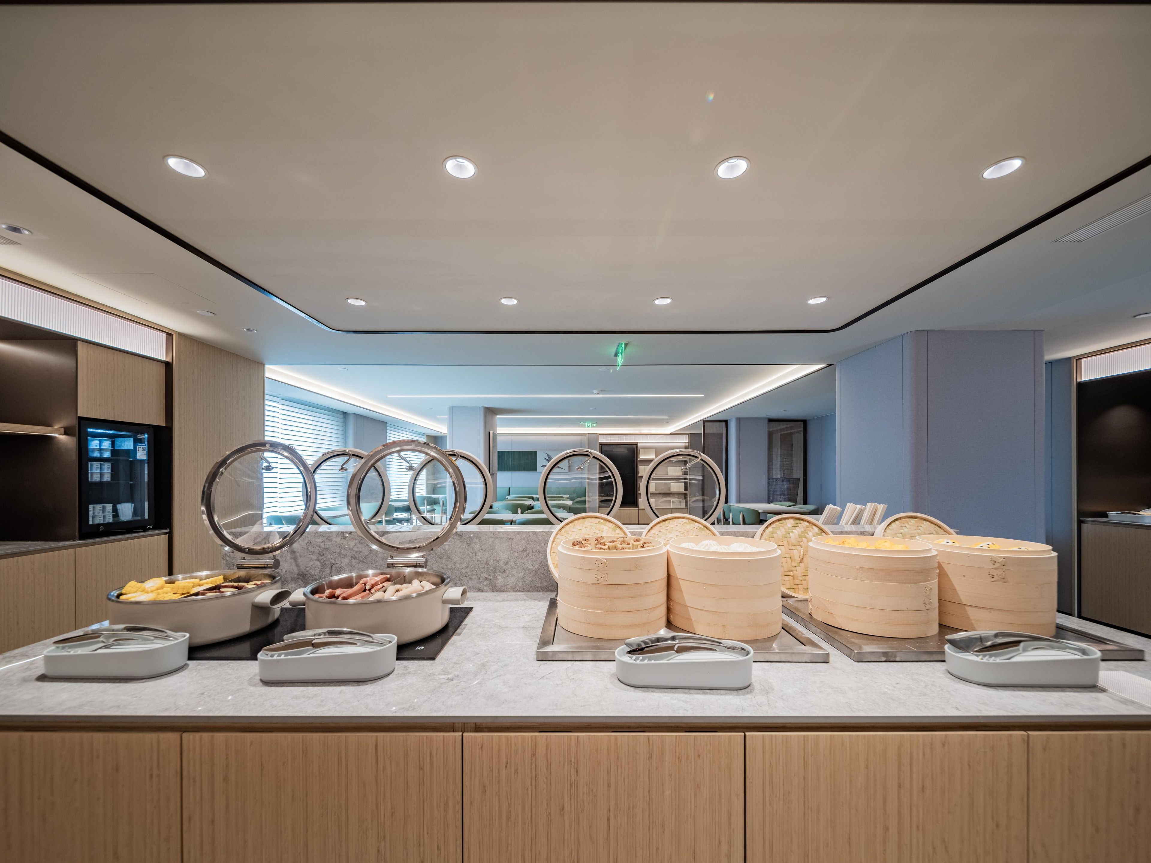 A buffet area with multiple food stations, including a bowl of fruit, a pot of soup, and several containers of rice.