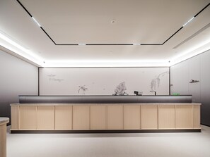 A modern bathroom with a wooden vanity, recessed lighting, and wall art.