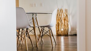 A dining area with a table and chairs, a wooden floor, and a decorative wall piece. - The Spot (Winnipeg)