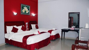 A hotel room with two beds, a desk, and a mirror. - Hotel Benua Bandung (Bandung)