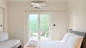 A hotel room with a bed, a sofa, a balcony, and an air conditioning unit.