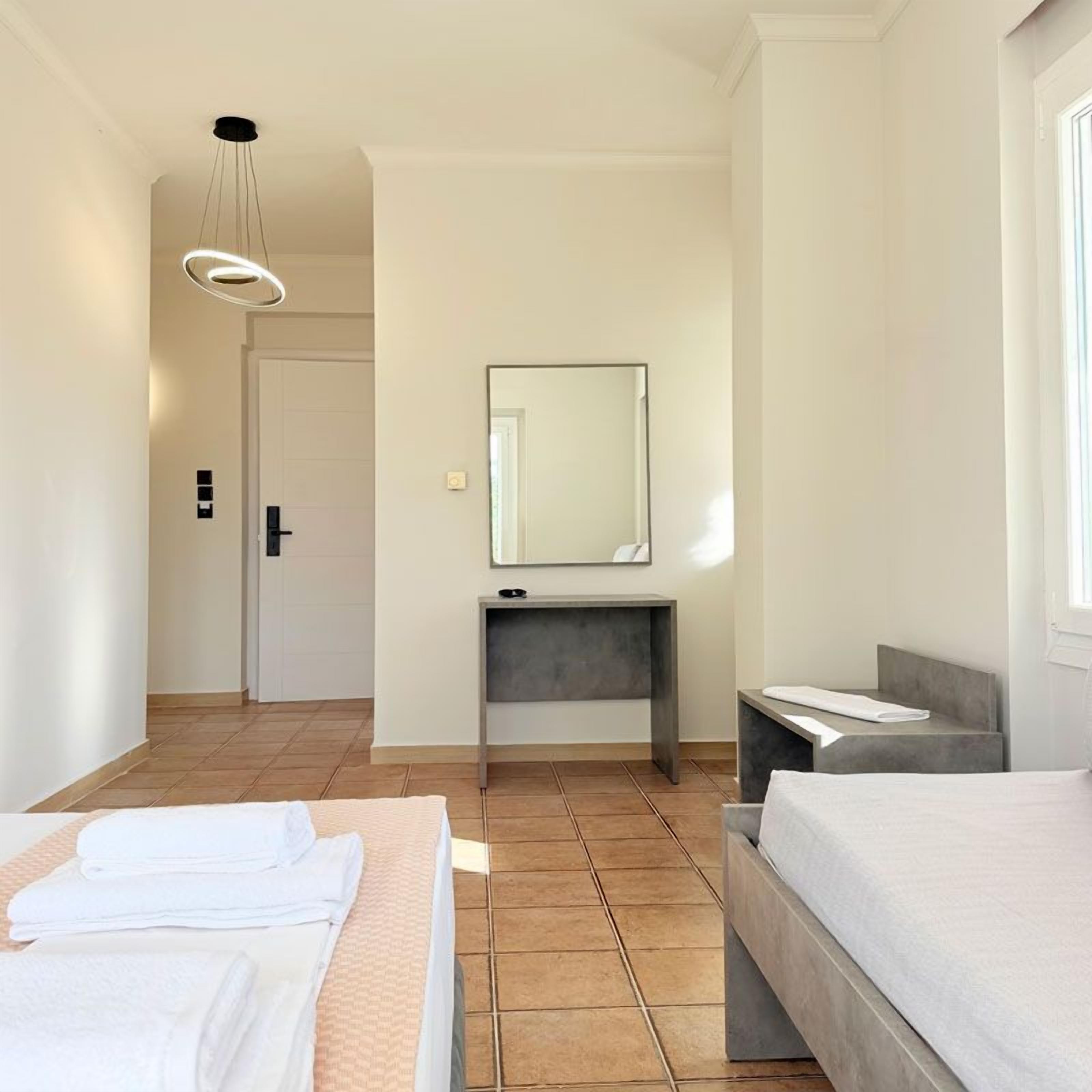 A hotel room with a bed, a desk, a mirror, and a window.