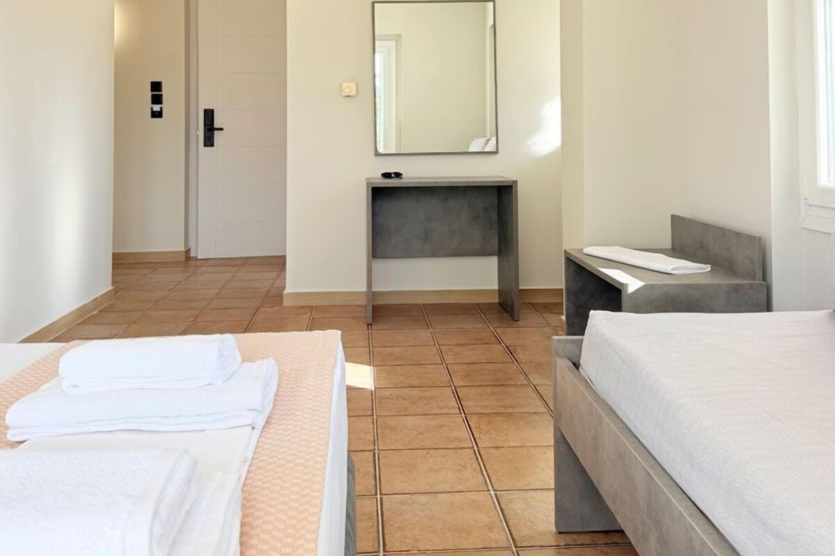 A hotel room with a bed, a desk, a mirror, and a window.