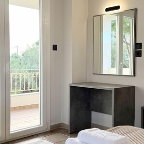 A bathroom with a large mirror, a dark sink, and a view of a balcony.