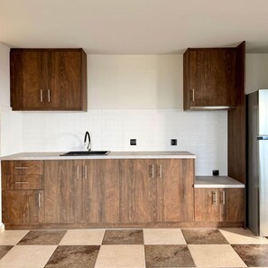 A kitchen with wooden cabinets, a white countertop, and a tiled floor.