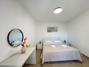 Una habitación de hotel con cama, mesitas de noche, un espejo, una obra de arte en la pared y una lámpara en el techo.