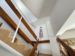 Una escalera con vigas de madera, una pared de piedra y un cuadro en la pared.