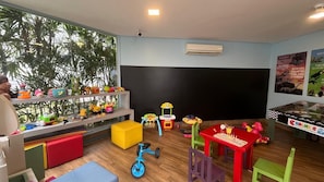 A children's playroom with toys, a chalkboard, and a window with a view of trees. - Ultimate Comfort in a Modern Room – Explore Nearby National Park! (Paraná)