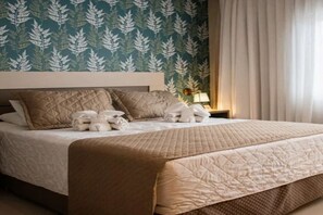 A neatly made bed with a quilted cover, a headboard, and a wall with a leafy pattern. - Perfect for Spa-Goers! Elegant Room in the Heart of Foz do Iguaçu (Paraná)