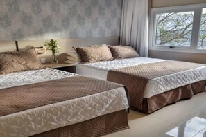 Una camera da letto con due letti, un comodino con un vaso e una finestra vista.