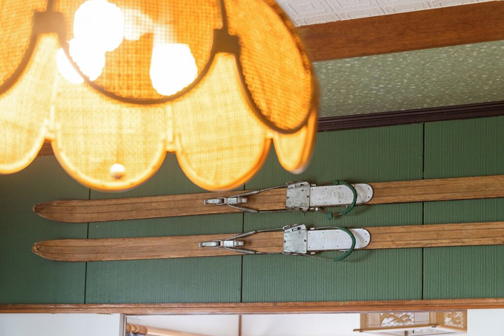 A room with wooden flooring, a green wall, and a ceiling with a light fixture.