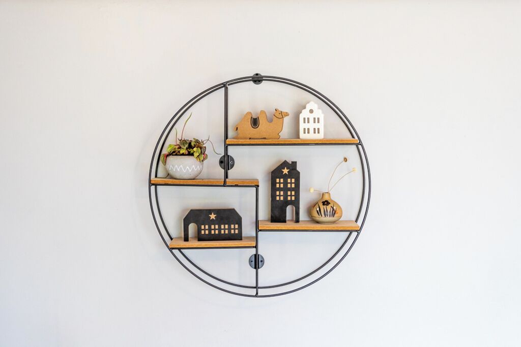 Uno scaffale circolare fissato al muro, decorato con diversi oggetti.