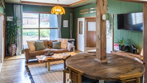 Un salon chaleureux avec une table à manger en bois, un canapé et un téléviseur fixé au mur.
