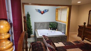 Un baño con una bañera grande, un espejo, un aparador de madera y un adorno de pared.