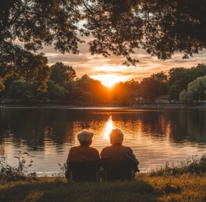 Dues persones assegudes al costat d'un llac al capvespre.