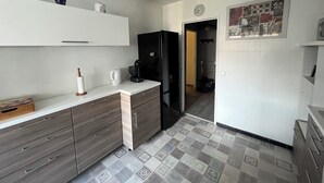 Una cocina con un refrigerador negro, una cafetera y un armario blanco.
