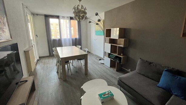 Una sala de estar con una mesa de comedor, sofá y televisor.