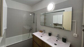 Un baño con cabina de ducha de vidrio, tocador doble y espejo con luz.