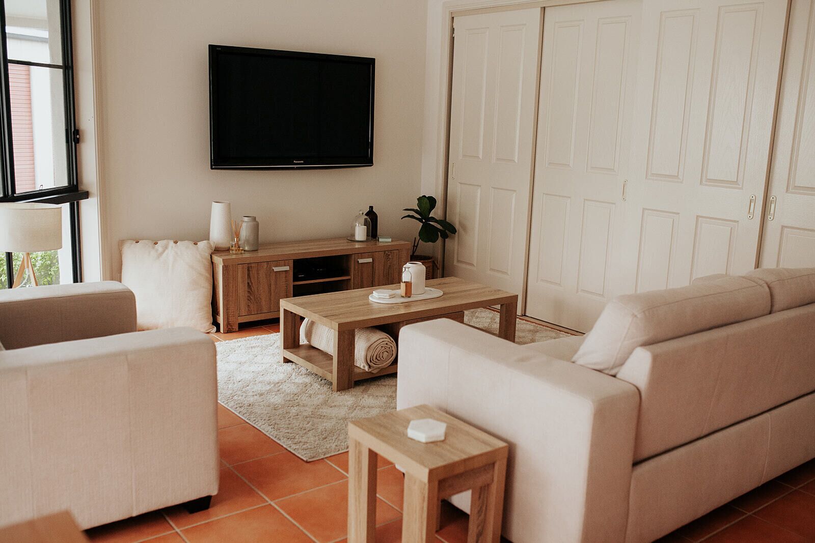 Een woonkamer met een bank, een salontafel, een televisie en een kast.