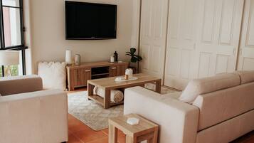 Een woonkamer met een bank, een salontafel, een televisie en een kast.