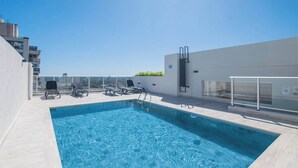 Ein Pool auf dem Dach mit Liegestühlen und einer Glasbrüstung.