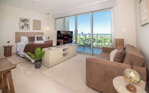 A modern living room with a bed, a TV, a sofa, a coffee table, and a balcony with a view. - Corporate Stays The Avenue (Asunción)