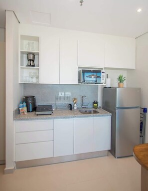 A modern kitchen with white cabinets, a stainless steel refrigerator, a microwave, and a coffee maker. - Corporate Stays The Avenue (Asunción)