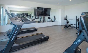 A gym with treadmills, weight machines, and a TV on the wall. - Corporate Stays The Avenue (Asunción)