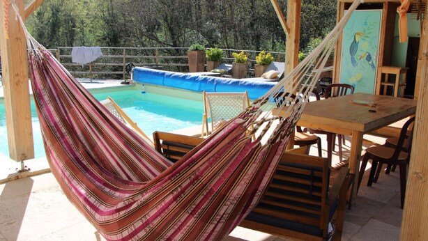 A hammock, pool, wooden deck, and outdoor seating area.
