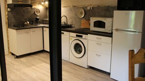 A compact kitchen with a washing machine, microwave, and a refrigerator.