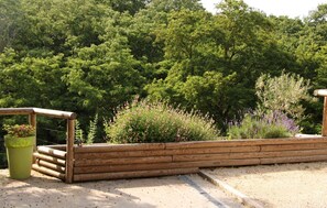 Ein Holzzaun mit einem Blumenkasten auf der linken Seite und verschiedenen Pflanzen im Hintergrund.