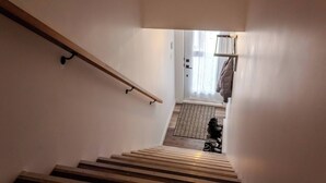 Una scala conduce a una stanza con un tappeto decorato e un appendiabiti.