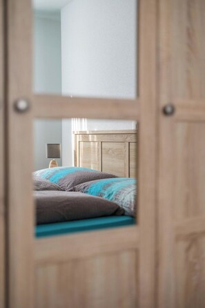 A bedroom with a wooden headboard, a bed with multiple pillows, and a nightstand with a lamp. - Alpen Leukerbad # 4-bed apartment, Dusche, WC by Interhome (Leukerbad)