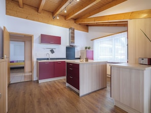 A modern kitchen with wooden beams, a central island, and a window providing natural light. - Alpen Leukerbad # 4-bed apartment, Dusche, WC by Interhome (Leukerbad)