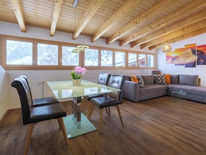 A spacious living area with a glass dining table, leather chairs, a gray sofa, and a wooden ceiling. - Alpen Leukerbad # 4-bed apartment, Dusche, WC by Interhome (Leukerbad)