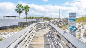 Un muelle de madera que conduce a una playa, con un letrero sobre el Programa de Playas Saludables de Florida.