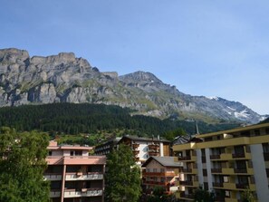 A mountain town with buildings in the foreground and a large mountain in the background. - Fortuna 302 # 3-bed apartment, Dusche, WC 3-Bettwohnung, Dusche, WC by Interhome (Leukerbad)