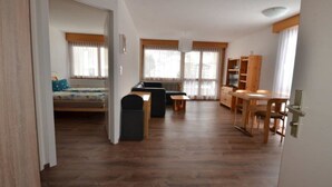 A spacious living area with a sofa, a dining table, and a kitchenette. - Fortuna 302 # 3-bed apartment, Dusche, WC 3-Bettwohnung, Dusche, WC by Interhome (Leukerbad)
