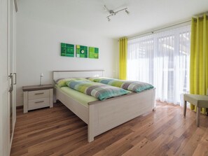 A bedroom with a bed, bedside tables, a bench, and artwork on the wall. - Alpen Leukerbad # 4-bed apartment, Dusche, WC by Interhome (Leukerbad)