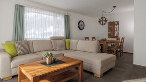 En stue med en hjørnesofa, et træ sofabord og et spiseområde med et træbord og stole.