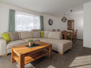 A living room with a sectional sofa, a wooden coffee table, and a dining area with a wooden table and chairs. - Alpen Leukerbad # 4-bed apartment, Dusche, WC by Interhome (Leukerbad)