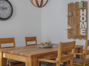 A wooden dining table with chairs, a wall clock, and a wooden shelf with the word 'HOME' on it. - Alpen Leukerbad # 4-bed apartment, Dusche, WC by Interhome (Leukerbad)