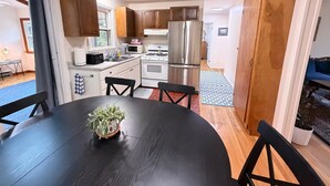 A modern kitchen with white cabinets, stainless steel appliances, and a dining area with a black table and chairs. - 2Bed 1Bath- ½ Mile walk to Mayflower, central A/C, CLEAN w/ washer/dryer (Dennis)