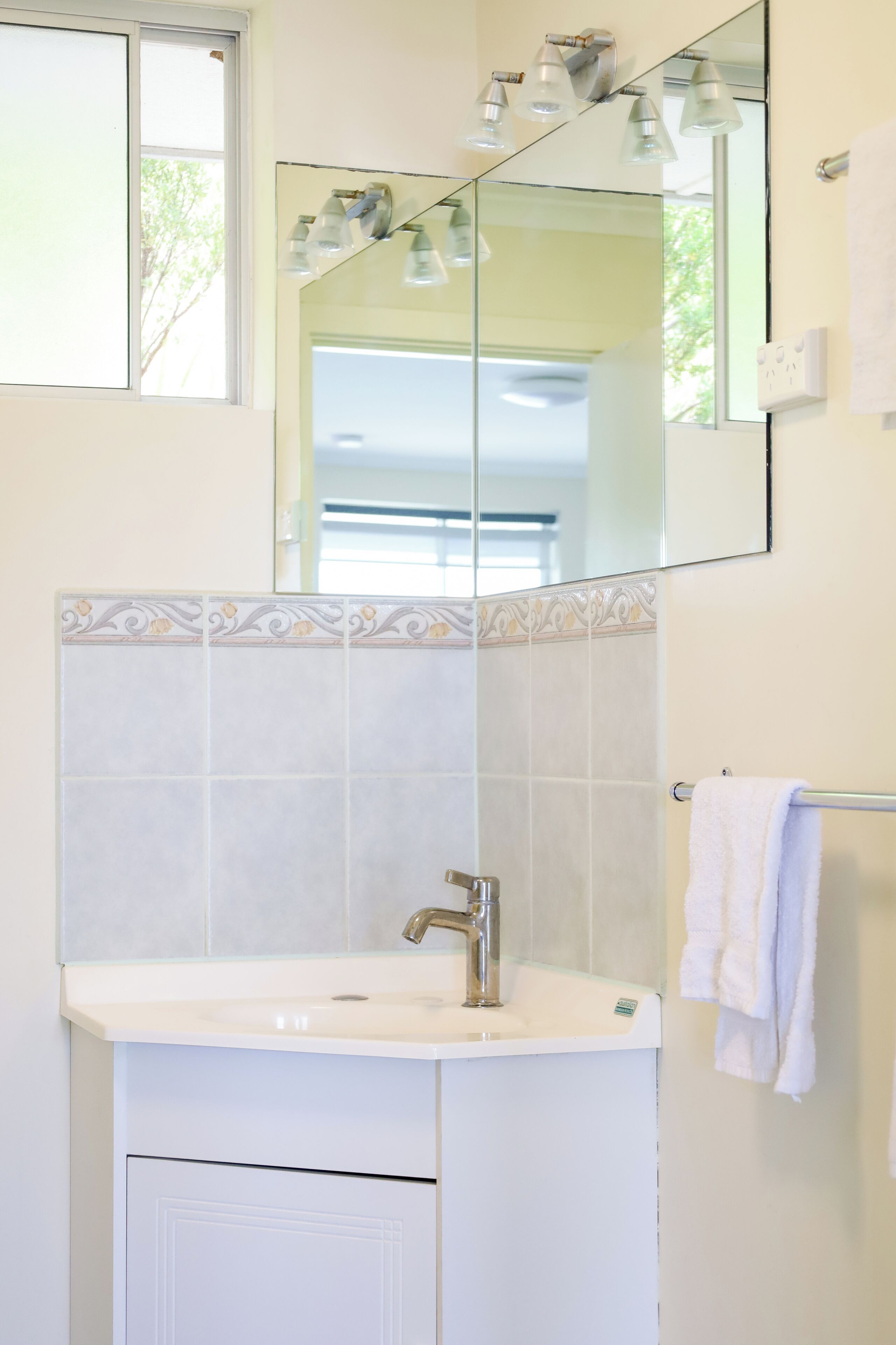 A bathroom with a white sink, a mirror, and a towel rack.