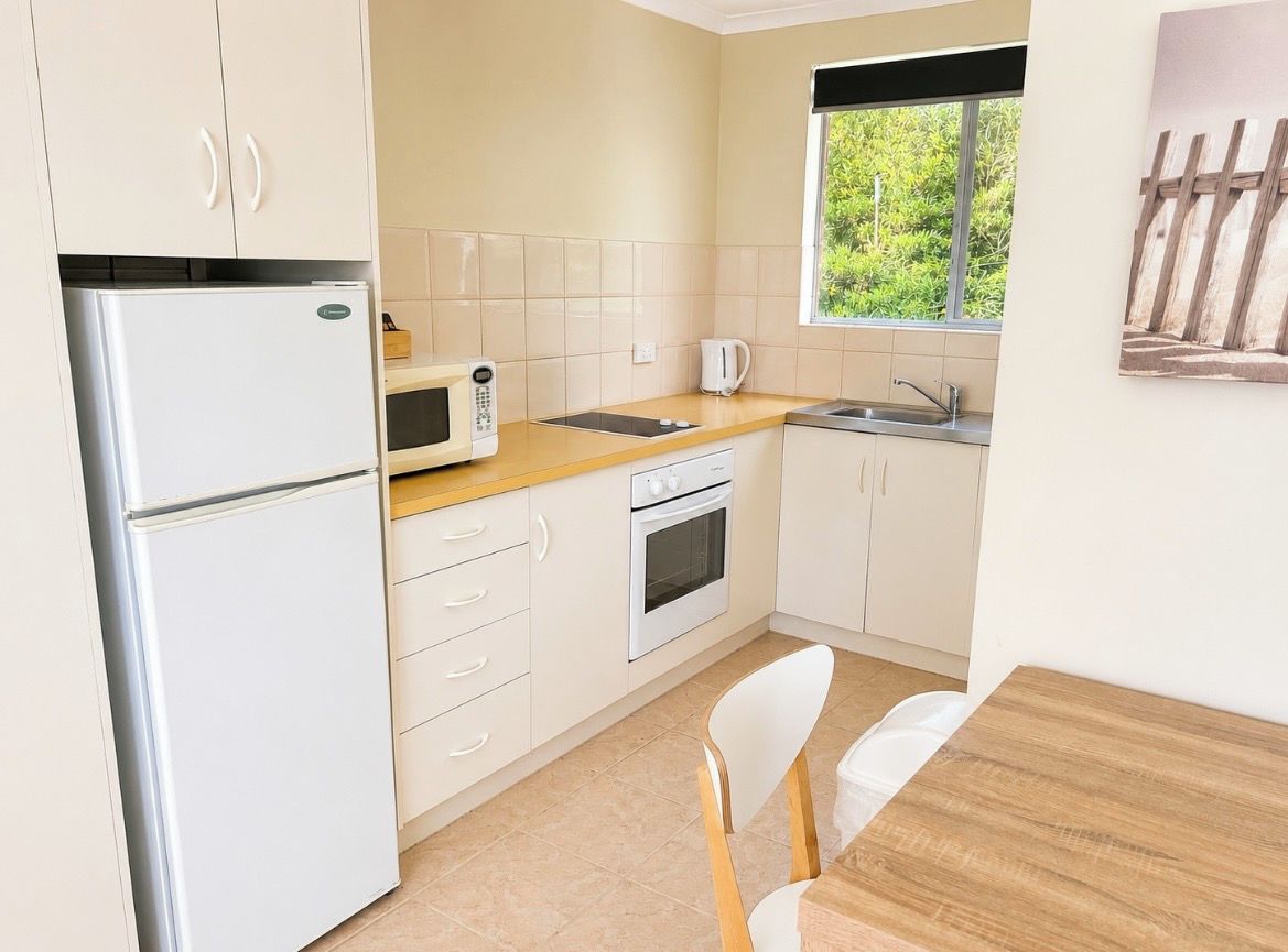 A compact kitchen with a refrigerator, microwave, oven, and sink.