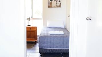 Un dormitorio con una cama, una mesita de noche, un cuadro en la pared y una ventana.